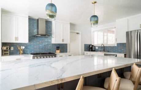 San Diego Kitchen Remodel, blue-coastal Open-concept coastal kitchen in Clairemont, San Diego, featuring a massive quartz island, white cabinetry, and blue pendant lighting.