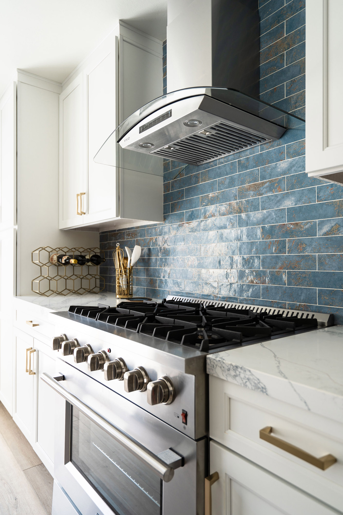 San Diego Kitchen Remodel, blue-coastal Coastal kitchen remodel in San Diego featuring a stainless steel gas range, curved glass hood, textured blue tile, and quartz counters.